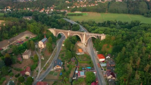Luchtfoto van de oude brug viaduct in groen hout in de buurt van het dorp. Spoorweg over vallei. — Stockvideo