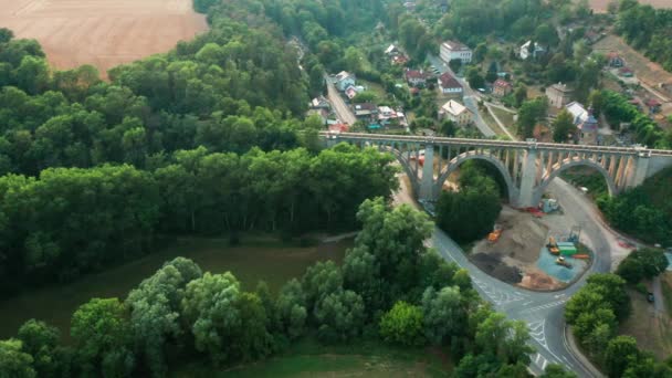 Flygvy över gamla bron viadukten i grönt trä nära byn. Järnväg över dalen. — Stockvideo