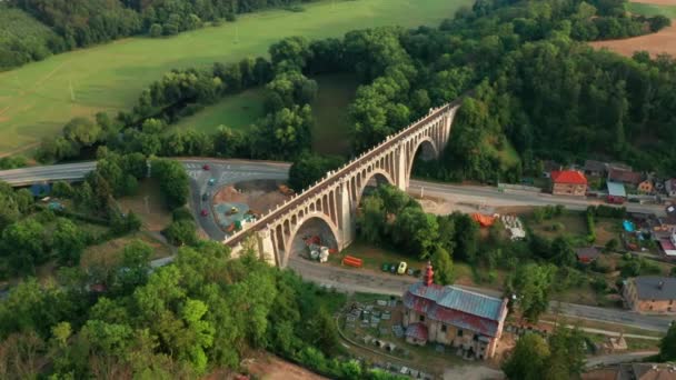 Luftaufnahme des alten Brückenviadukts im grünen Wald in der Nähe des Dorfes. Eisenbahn über Tal. — Stockvideo