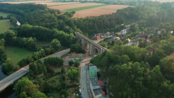 Luchtfoto van de oude brug viaduct in groen hout in de buurt van het dorp. Spoorweg over vallei. — Stockvideo