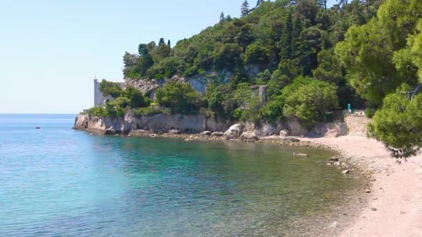 Sur les montagnes rocheuses se trouve un château au-dessus d'une eau de mer bleue. Dans la région éloignée est château sur les montagnes fendues sur la clairière de la mer .