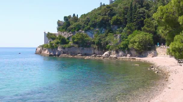 Na skalistych górach znajduje się zamek nad błękitną wodą morską. W odległej okolicy znajduje się zamek w górach szczelinowych nad morzem Polana. — Wideo stockowe