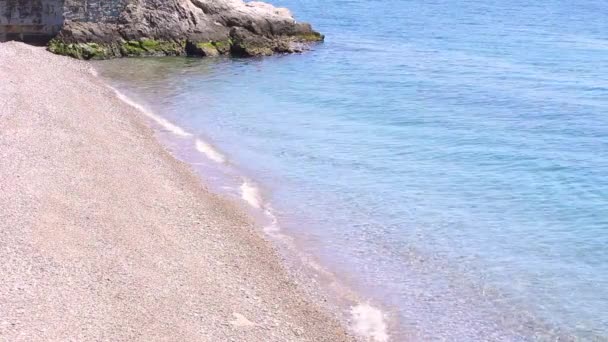 Increíble vista sobre la playa junto al mar con agua azul, arena amarilla y una pequeña roca en la esquina de la foto. Una hermosa playa de mar Adriático con arena amarilla-blanca y agua limpia y transparente . — Vídeo de stock