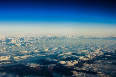 Alp Dağları ve Tepeleri 'nin panoramasındaki uçaktan hava görüntüsü. Bulutlar ve sis ile kaplı kayalardan oluşan dağ zirvesi. Dağ manzarası yukarıdan görünüyor.