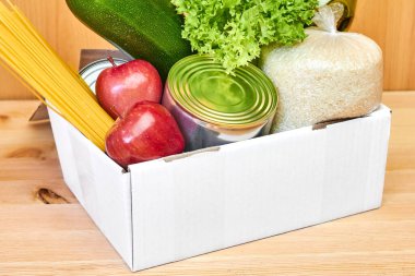 Tahta arka planda farklı sağlıklı ürünlerin olduğu beyaz kutuyu kapat. Süpermarketten ya da internetten yiyecek teslimatı hizmeti