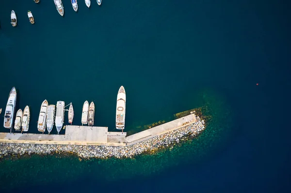 Bovenaanzicht op een haven met aangemeerde jachten, boten en schepen in donker zeewater. — Stockfoto