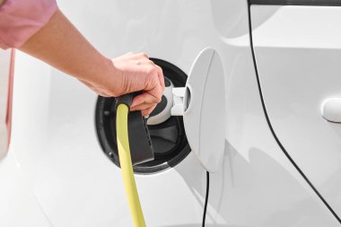 Elektrikli araba prizinden şarj aletinin fişini çeken kadın. Sıfır emisyonlu çevre dostu araç 