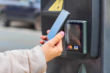 NFC teknolojisi kullanılarak park ücreti Visa ve Mastercard desteklendi. Yakın plan kadın eli ödeme için akıllı telefon kullanıyor.. 