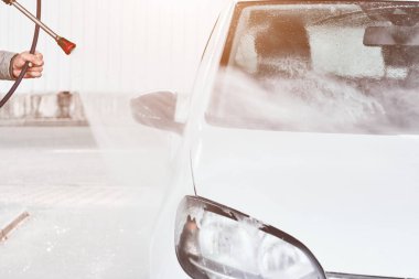 Kapıları kapatın ve yüksek basınçlı suyla beyaz bir arabayı yıkayın. Araba yıkama servisi..