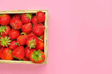 Ahşap sepetin içinde pembe bir arka planda mahçup alanı olan çilek. Taze taze organik böğürtlen