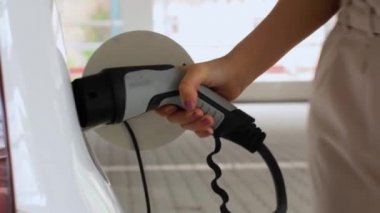 Elektrikli bir arabaya elektrik kablosu takan bir kadın. Sıfır emisyon aracı, Haziran 2020, Prag, Çek Cumhuriyeti.