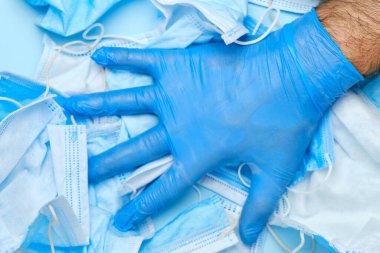 İnsanlar kullanılmış koruyucu yüz maskelerinin arka planında lastik mavi eldiven veriyorlar. Coronavirüs salgınından sonra tıbbi çöpler. Karantinanın sonu. 