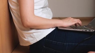 Yakından bir kadın dizüstü bilgisayarıyla yerde oturuyor. Coronavirus karantinası sırasında merkez ofis kavramı.