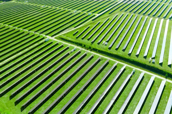 Вид сверху на солнечные панели в поле с зеленой травой. Большая современная солнечная станция, производящая возобновляемую энергию. Экологическая электростанция . — стоковое фото