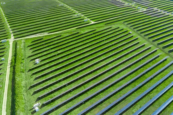 Вид сверху на солнечные панели в поле с зеленой травой. Большая современная солнечная станция, производящая возобновляемую энергию. Экологическая электростанция . — стоковое фото