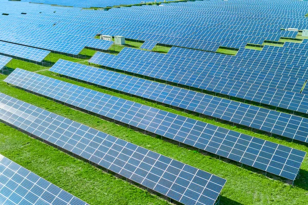 Closeup batteries de soleil énergie dans le domaine avec de l'herbe verte. Centrale solaire avec panneau bleu produisant des énergies renouvelables respectueuses de l'environnement. — Photo