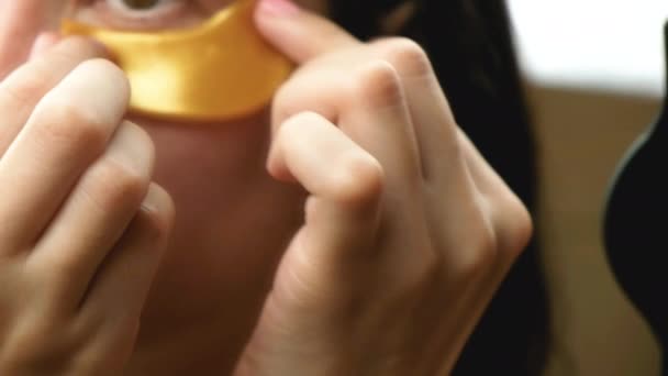 Mujer joven utilizó parches de colágeno dorado hidrogel bajo los ojos. Levantamiento de arrugas. Cuidado de la piel en casa. Procedimiento de cosmetología . — Vídeos de Stock