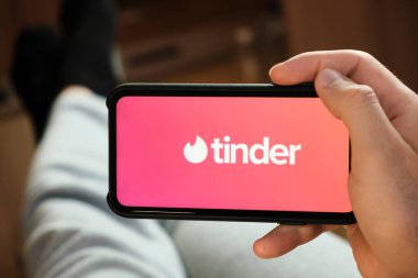 Akıllı telefon ekranında Tinder logosu var. Flört ve aşk için Tinder uygulaması kullanan adam, Temmuz 2020, Prag, Çek Cumhuriyeti.