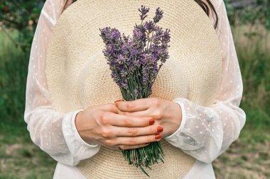 Elinde bir şapka ve bir demet lavanta tutan bir kadın. Kaynak kırsal stye