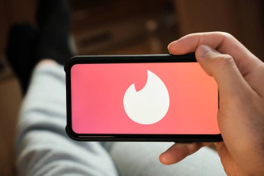 Tinder logosu akıllı telefon ekranında, Tinder uygulamasını flört ve aşk için kullanan adam, Temmuz 2020, Prag, Çek Cumhuriyeti.