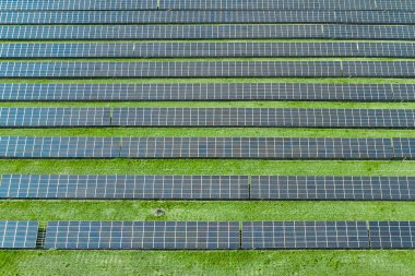 Yeşil çimenli, yatay güneş panelinin hava görüntüsü. Yeşil, çevre dostu, elektrik üretimi için yenilenebilir enerji kaynağı. Büyük güneş enerjisi istasyonu.