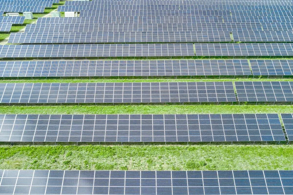 Vista aérea del panel solar horizontal en el campo con césped verde. Fuente de energía verde, ecológica y renovable para la producción de electricidad. Gran central solar . — Foto de Stock