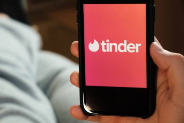 Tinder logosu akıllı telefon ekranında, Tinder uygulamasını flört ve aşk için kullanan adam, Temmuz 2020, Prag, Çek Cumhuriyeti.