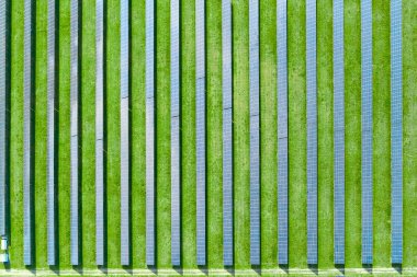 Elektrik üretimi için güneş enerjisi istasyonunun en üst görüntüsü. Yeşil alanda dikey güneş panelleri var. Yenilenebilir çevre dostu enerji kaynağı.