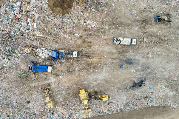 Garbage pile in trash dump or landfill. Dump trucks and excavators unloading waste