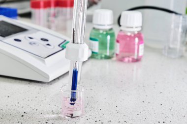Alkaliteyi ölçmek için cam elektrot ve arka planda kalibrasyon çözeltisi olan asitlik ölçer. Analitik veya elektro kimya laboratuvarı
