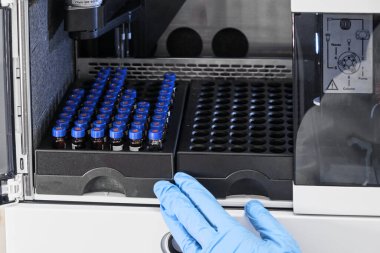 Mavi kapaklı cam şişeler otomatik yükselticili HPLC sisteminin rafında. Kimyasal ya da klinik laboratuvarında bileşiklerin ayrıştırılması. Bilimsel ve araştırma çalışmaları. Eczacılıkların geliştirilmesi.