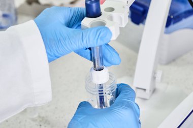 Lastik eldivenli bir kadın pH metre kullanarak çözeltinin pH 'ını ölçmek için cam elektrot tutuyor. Analitik veya elektro kimya laboratuvarı. 