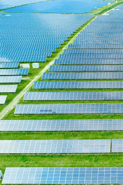 Letecký pohled na solární elektrárnu v zeleném poli pro výrobu elektřiny ze slunce. Fotovoltaický panelový systém pro výrobu zelené, ekologické, energetické. — Stock fotografie