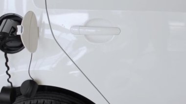 Şarj istasyonunda elektrikli araba veya EV şarj ediliyor. Şarj portuna bağlı kablo.