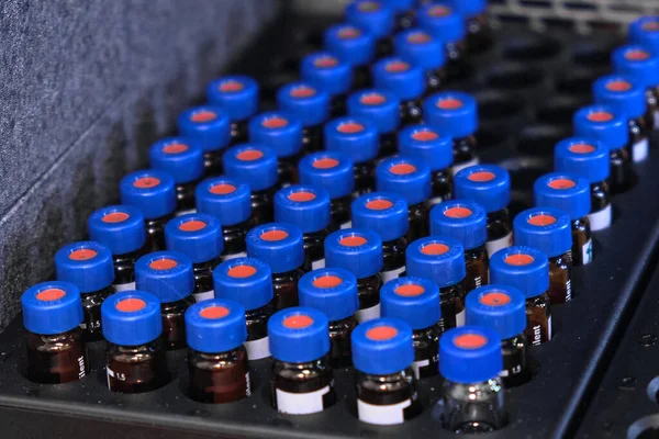 Glass vials with blue caps are in the rack of HPLC system with autosampler. Separation of compounds at chemical or clinical laboratory. Scientific and research work. Development of pharmaceuticals. — Stock Photo, Image