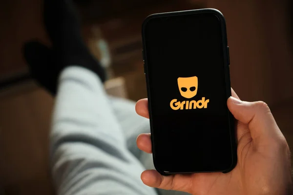 Erkek elinin altındaki akıllı telefondaki grindr uygulaması. Randevu ve buluşma için başvuru yapan bir adam. Sosyal ağ konsepti, Temmuz 2020, Prag, Çek Cumhuriyeti.