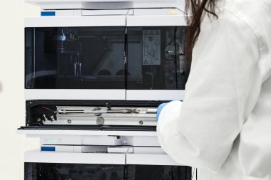 Kimyager ya da bilim adamı organik bileşikleri ayırmak için yüksek performanslı sıvı kromatografi HPLC sütununu değiştiriyor. Analitik kimya laboratuvarı. İşlem analiz ediliyor.