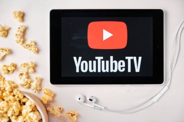 YouTube televizyonu, arka planda patlamış mısır kutusu ve Apple kulaklıkları olan tabletin ekranında. Reklam veya haber içeriği, Ağustos 2020, San Francisco, ABD