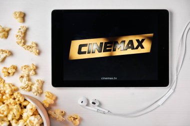 Patlamış mısır kutusu ve Apple kulaklıkları olan tabletin ekranında Cinemax var. Reklam veya haber içeriği, Ağustos 2020, San Francisco, ABD