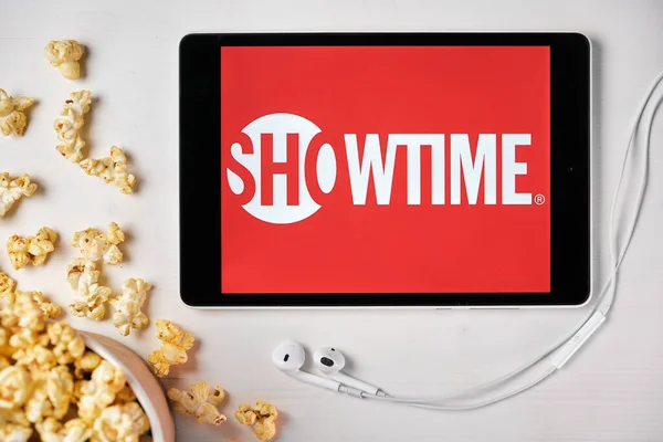 Logotipo Showtime en la pantalla de la tableta colocada en la mesa blanca y espolvoreado palomitas de maíz en ella. Auriculares Apple cerca de la tableta que muestra una aplicación Showtime, Agosto 2020, San Francisco, EE.UU. —  Fotos de Stock