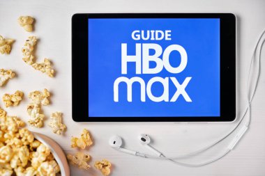 Beyaz masada duran tabletin ekranına HBO maksimum logosu koyun ve üzerine patlamış mısır serpin. Tabletin yanındaki Apple kulaklıklar HBO uygulamasını gösteriyor, Ağustos 2020, San Francisco, ABD
