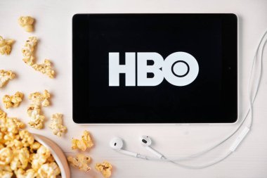 Beyaz masada duran tabletin ekranında HBO logosu ve üzerine patlamış mısır serpiştirilmiş. Tabletin yanındaki Apple kulaklıklar, Ağustos 2020, San Francisco, ABD
