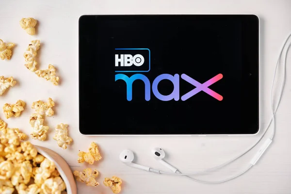 HBO MAX logo op het scherm van de tablet liggend op de witte tafel en besprenkelde popcorn erop. Apple koptelefoon bij de tablet, augustus 2020, San Francisco, Verenigde Staten — Stockfoto
