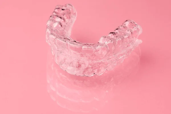 Two Invisible dental teeth aligners on the pink background. Orthodontic temporary removable braces for fixing teeth after alignment. Therapy after brackets. — Stock Photo, Image