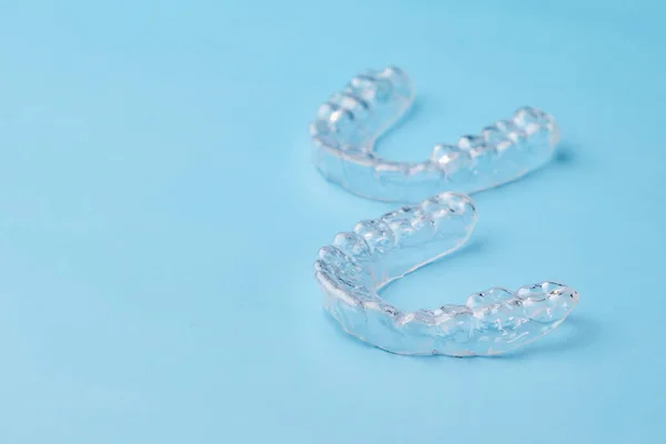 Alineadores de dientes extraíbles en el fondo azul con espacio de copia. Tratamiento ortodóncico para una sonrisa hermosa. — Foto de Stock