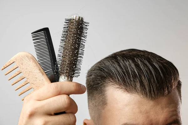 Close up wooden, plastic comb and round brush for styling haircut after barbershop. Product for mens hair care.