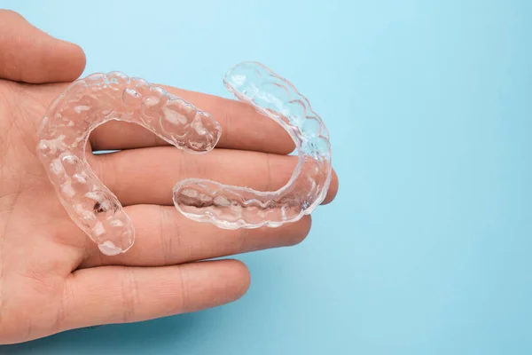 Kieferorthopäde hält in der Hand unsichtbare oder transparente herausnehmbare Zahnspangen für Zahnkorrekturen und Bleaching mit Kopierraum. — Stockfoto