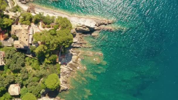 Declinando verso la costa rocciosa del mare bagnata da acqua verde turchese. Enormi pietre sott'acqua del Mar Ligure, Camogli, Italia. — Video Stock