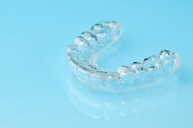 Mavi arkaplandaki görünmez hizalayıcıları fotokopi alanıyla kapat. Dişleri düzeltmek için plastik diş teli diş macunları..