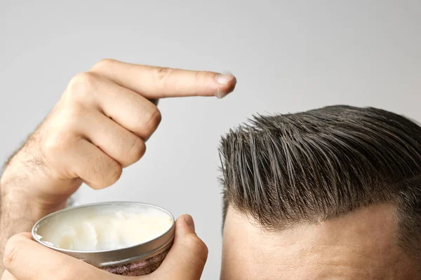 Man applying a clay, pomade, wax, gel or mousse from round metal box for styling his hair after barbershop hair cut. Advertising concept of mans products. Treatment and care against lost of hair — Stock Photo, Image